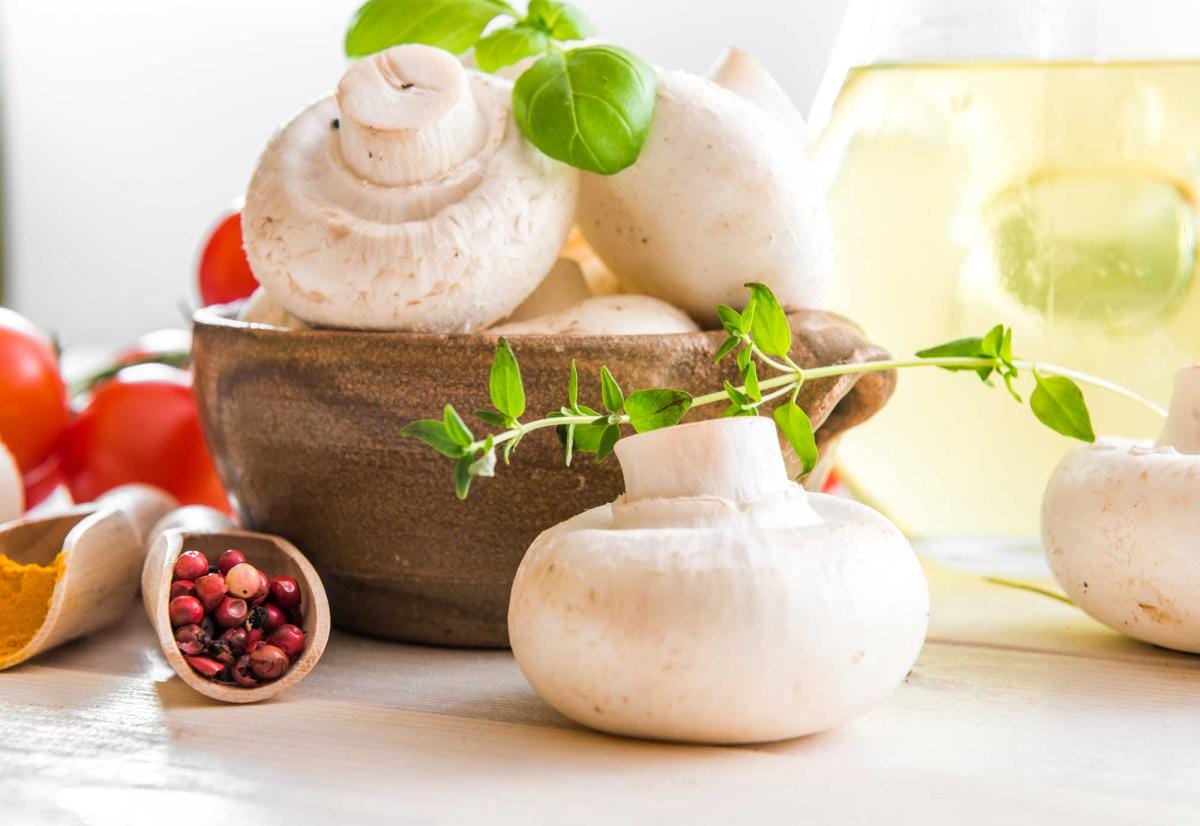 Fresh mushrooms, tomatoes, and herbs on wooden table