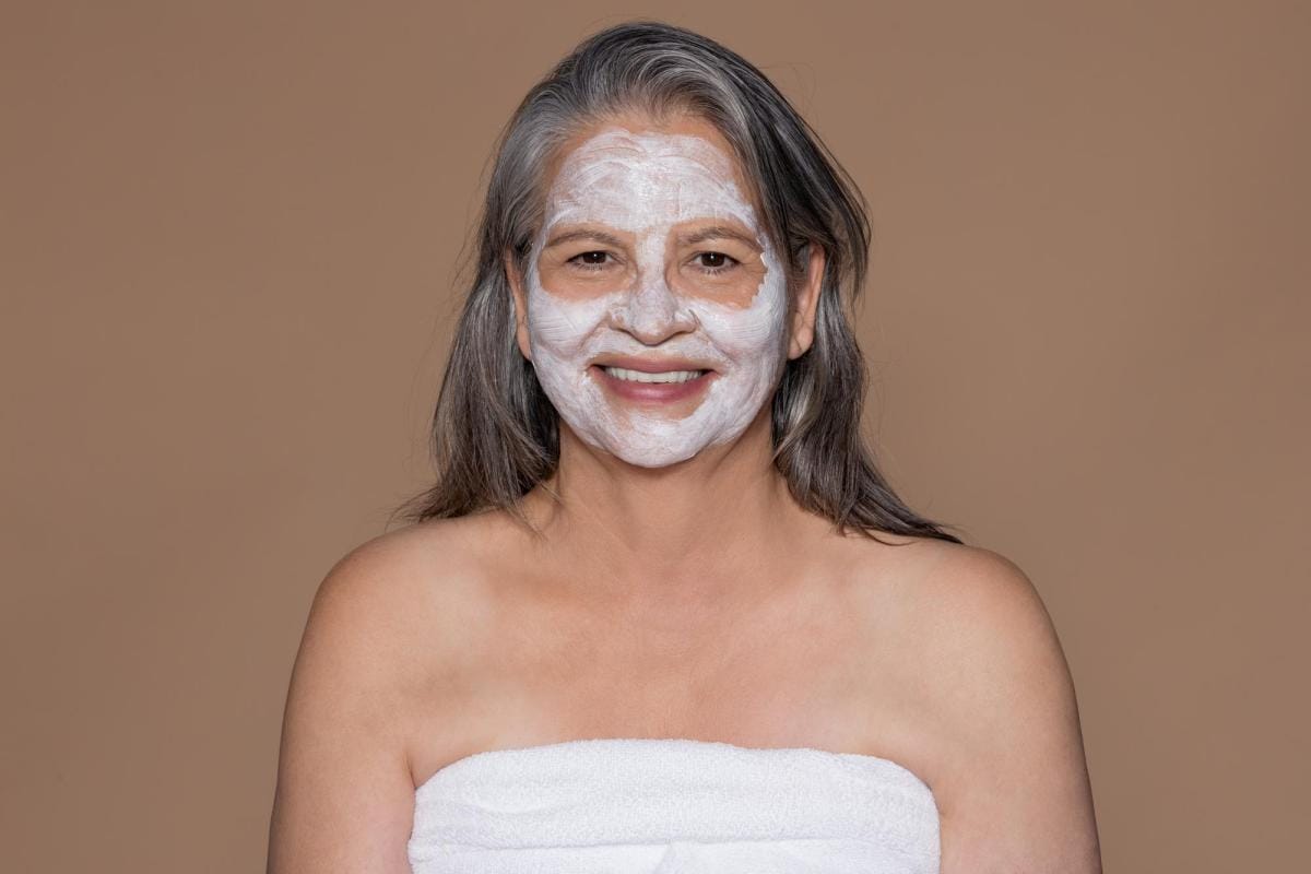 Senior woman smiling with facial mask treatment