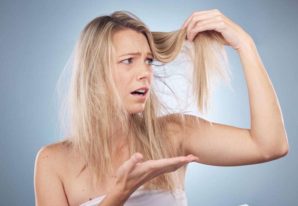 Woman inspecting damaged split ends of her hair