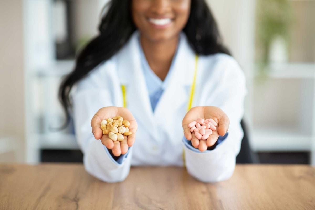 Nutritionist comparing pills and natural nuts in hands