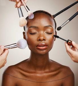 Woman getting makeup applied by multiple brushes