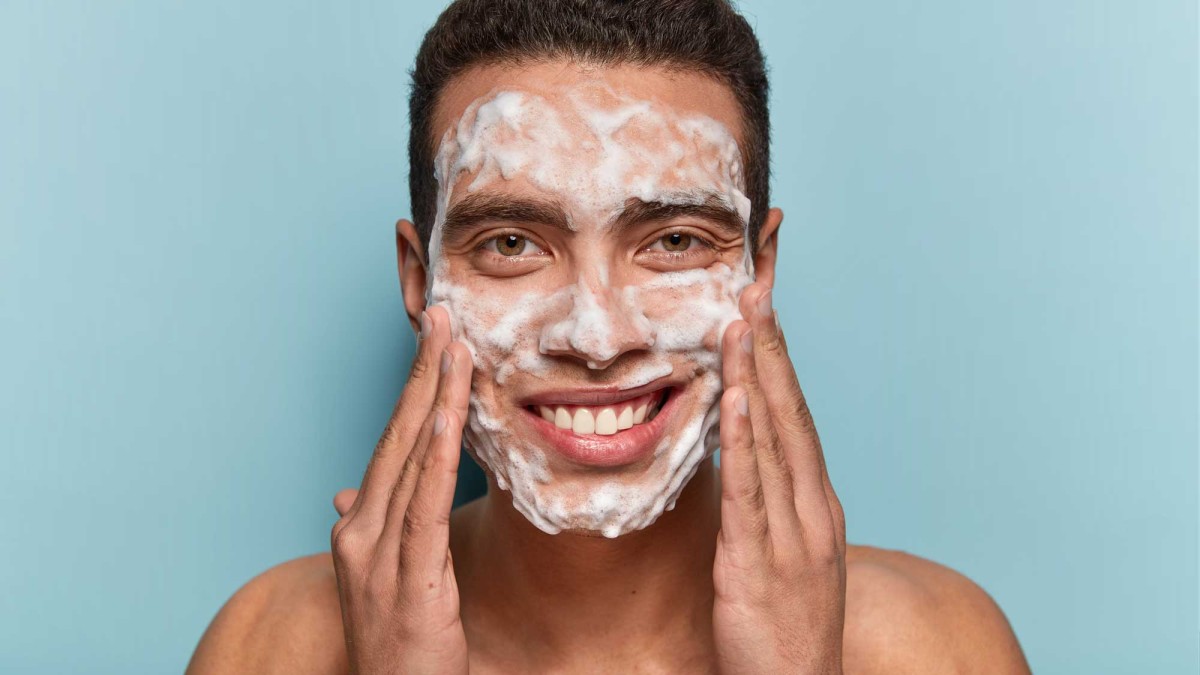 Man smiling with facial wash foam on face