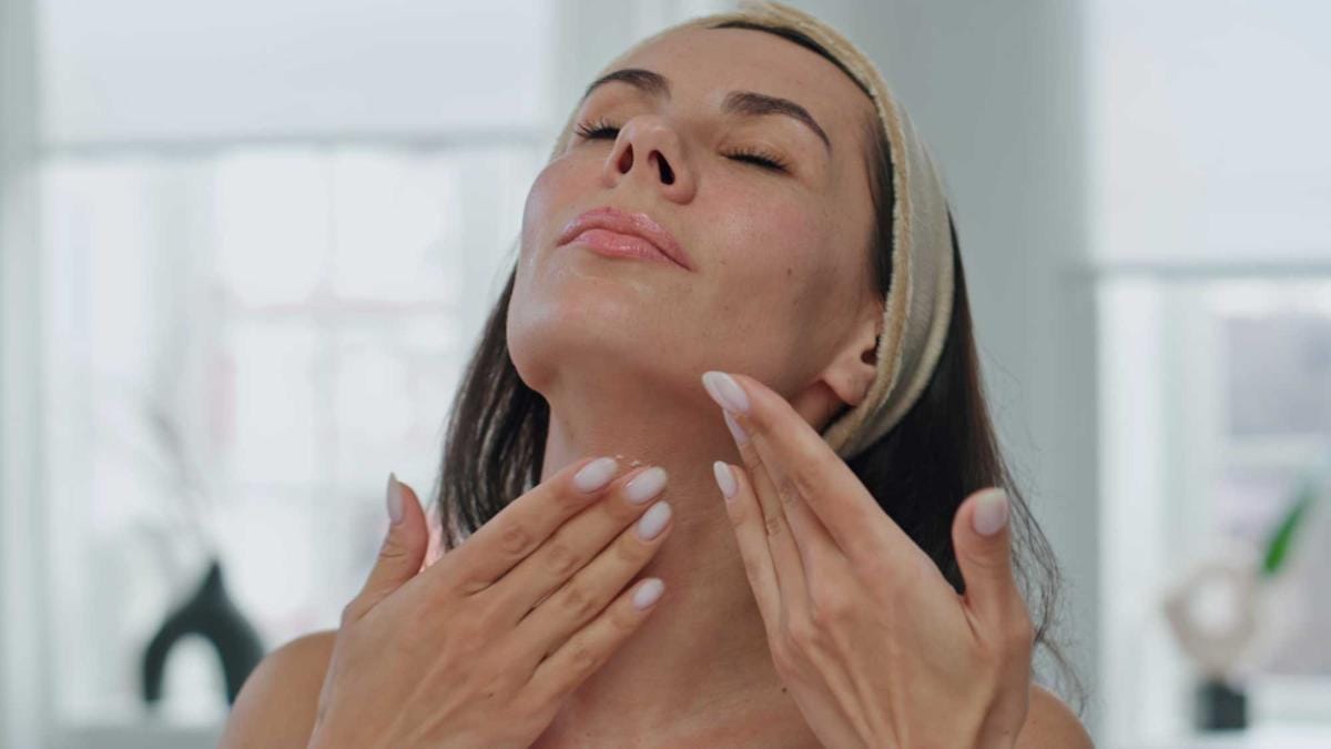 Woman applying skincare cream to neck and face