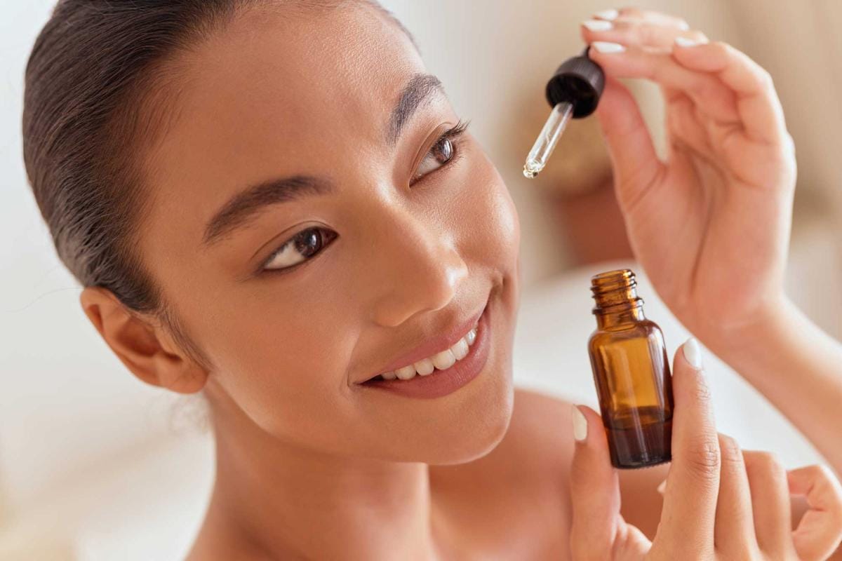 Woman applying facial serum from dropper