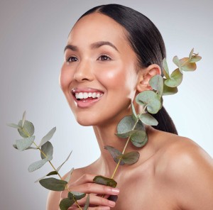 Joyful woman holding eucalyptus leaves, promoting natural skincare