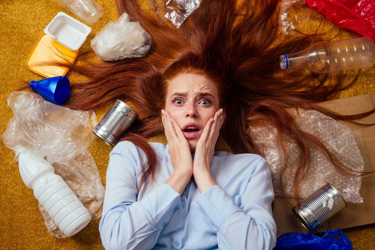 Shocked woman surrounded by assorted plastic garbage