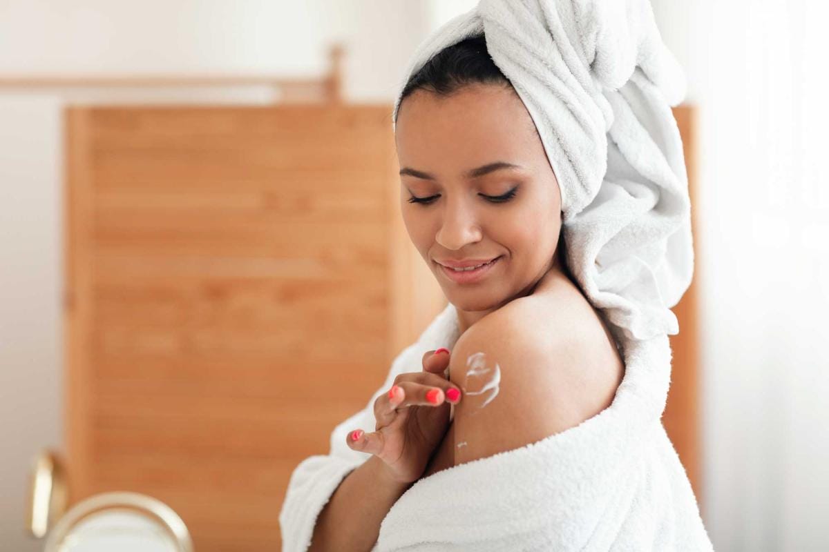 Woman applying lotion after shower