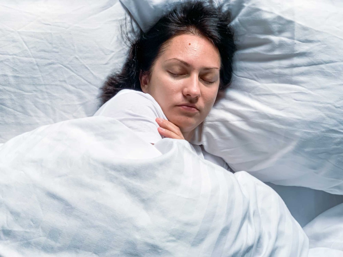 Woman sleeping peacefully in white bed linen