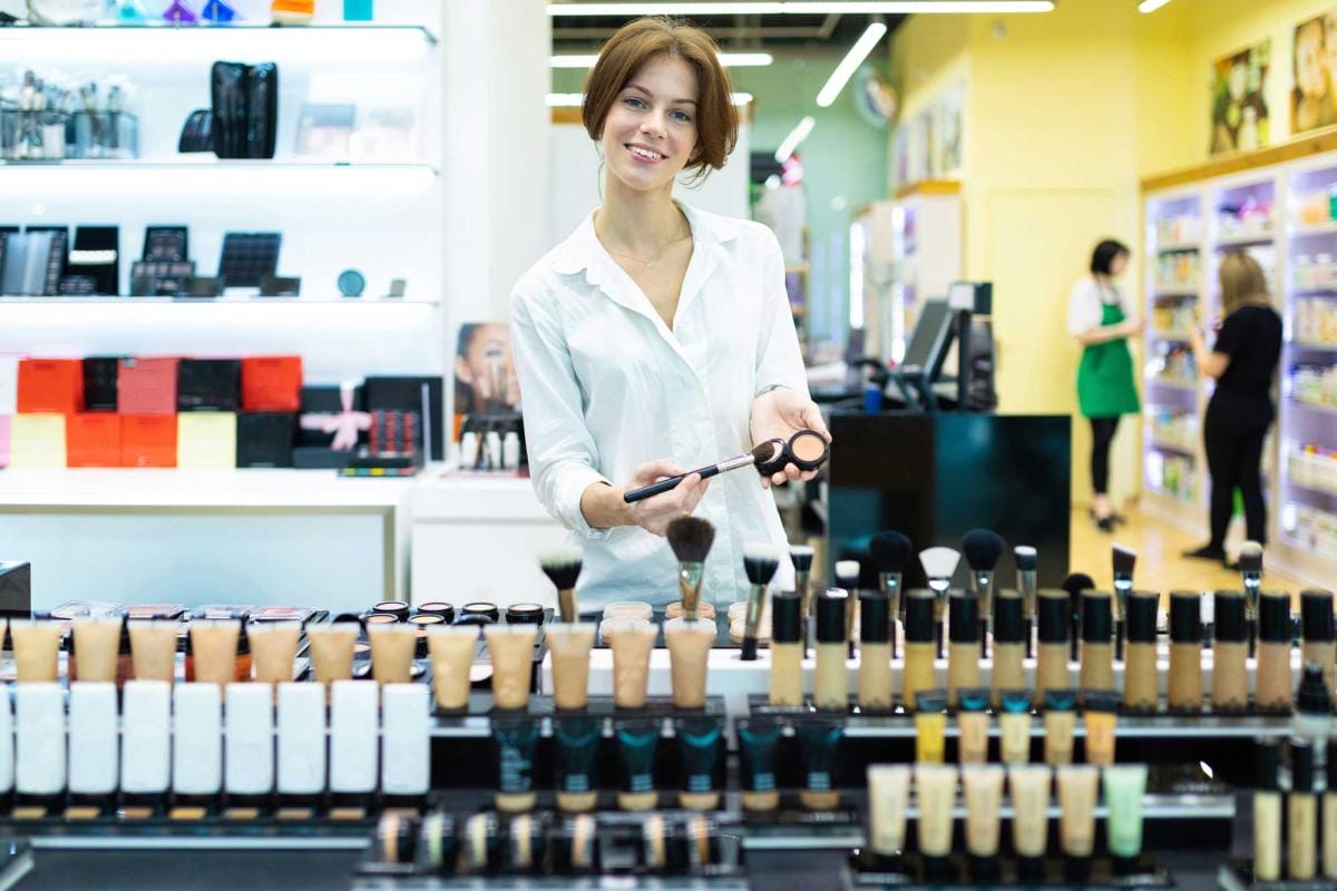 Woman demoing makeup brushes at cosmetics store