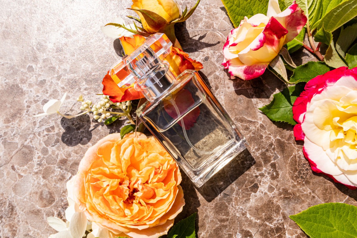 Perfume bottle surrounded by colorful roses on stone