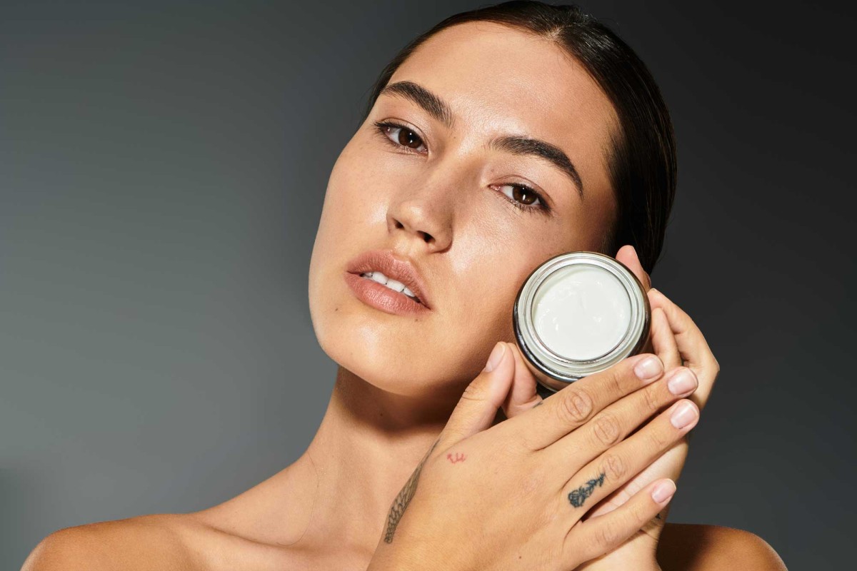 Woman holding skincare cream, looking serene