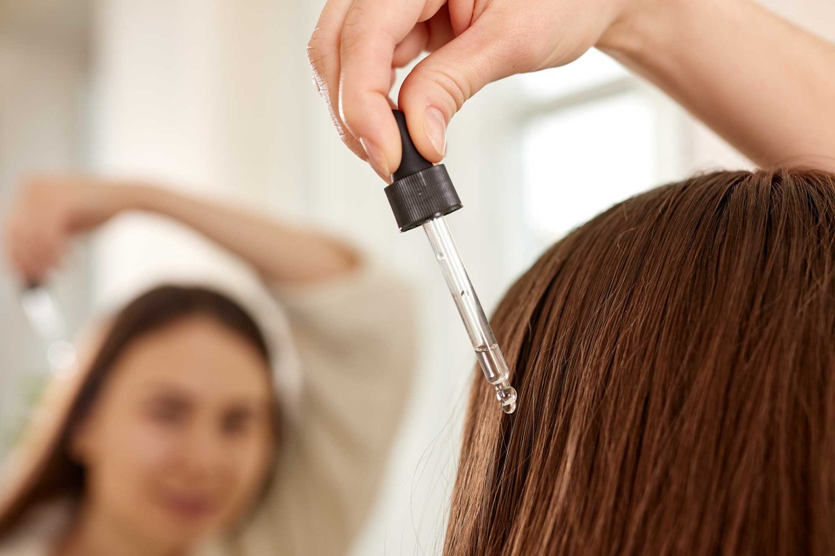 Hairdresser applying serum to woman's hair