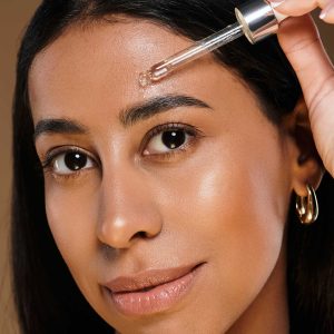 Woman applying serum on face with dropper