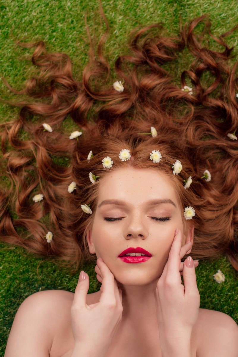 Woman with flowers in hair lying on grass