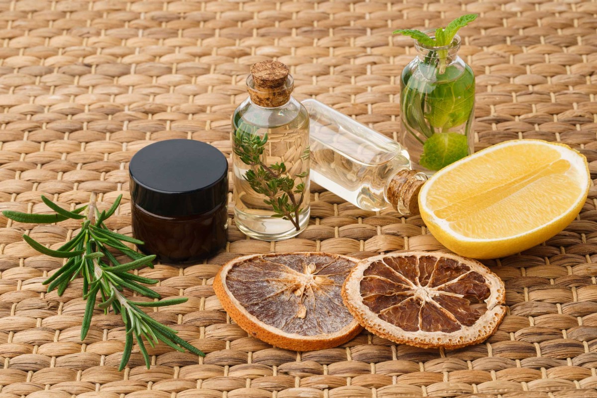 Essential oils with herbs and citrus on woven background