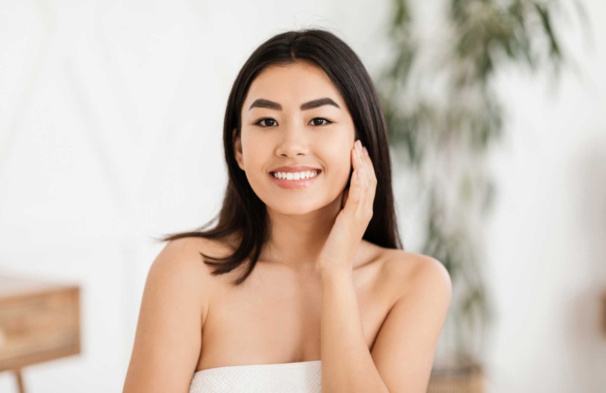 Young woman smiling, touching face gently in spa setting