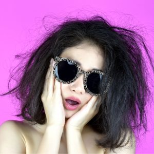 Woman in ornate sunglasses expressing surprise on pink background