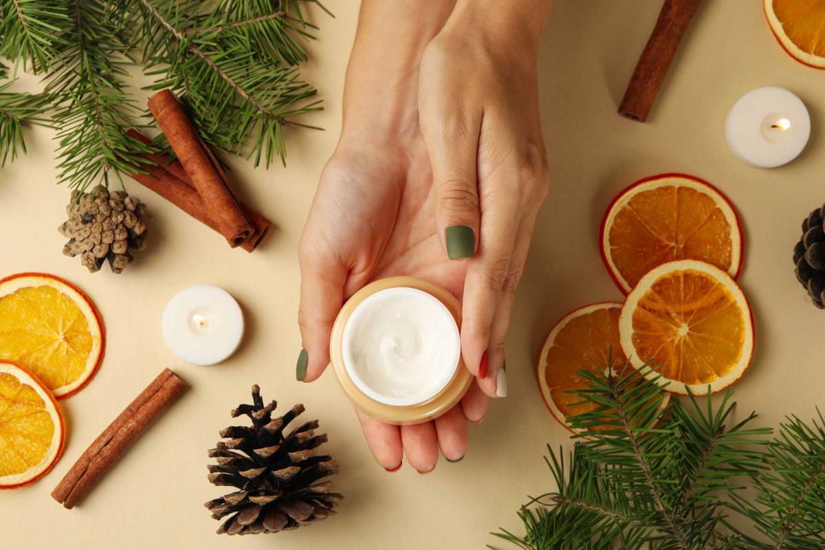 Hands applying cream amid festive winter decorations