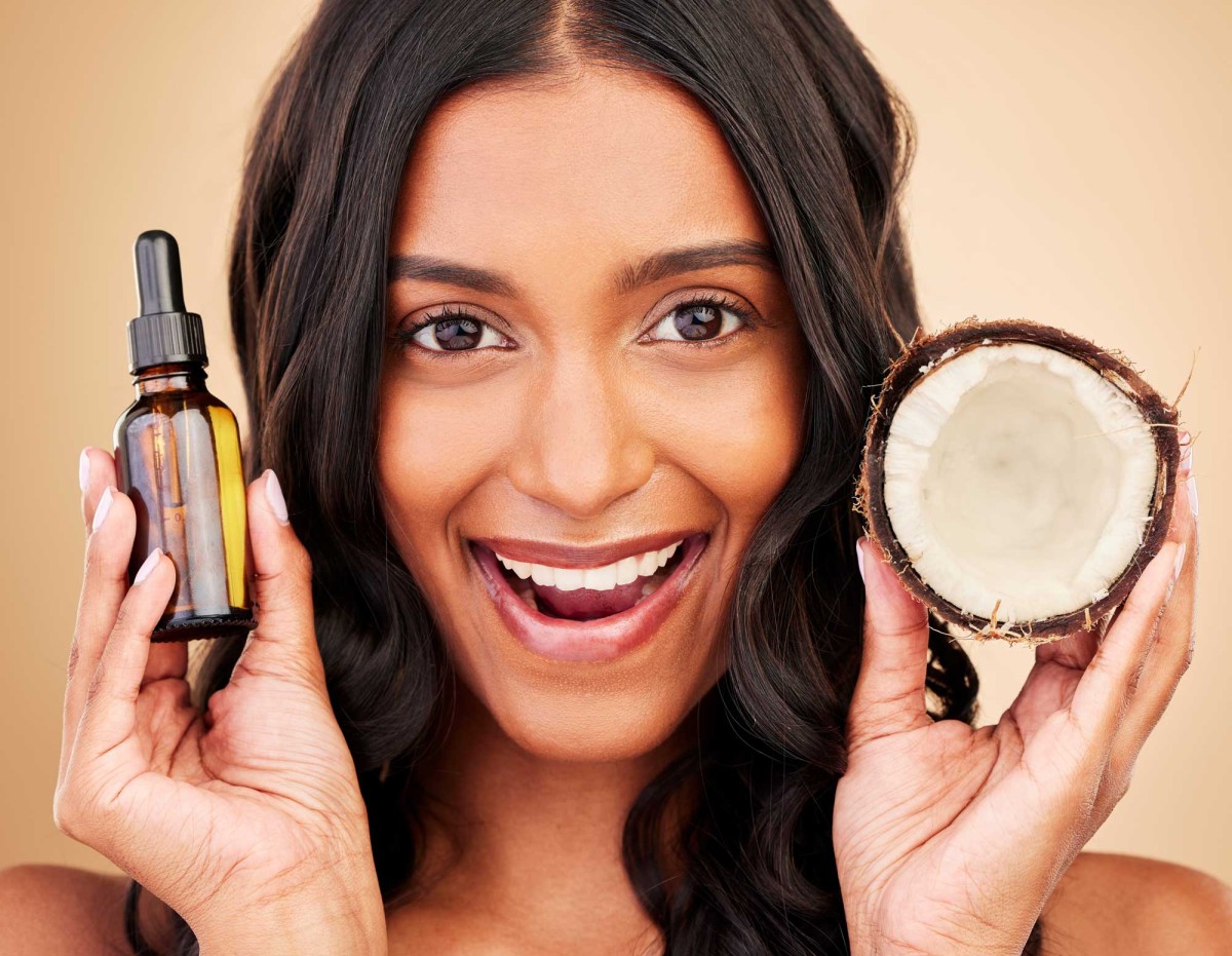 Woman smiling with coconut oil and dropper bottle