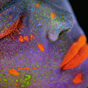 Close-up of colorful neon paint on woman's face