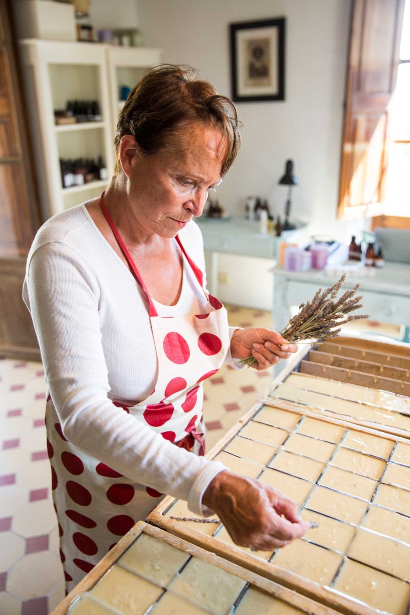 Woman making soap with lavender in kitchen workshop