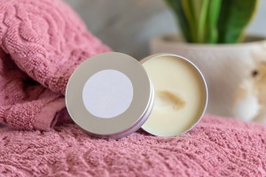 Open moisturizing cream on pink towel