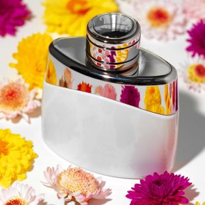 Floral painted perfume bottle surrounded by vibrant flowers