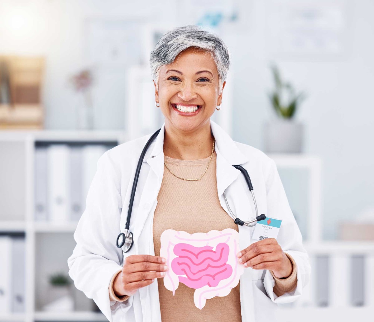 Smiling female doctor holding a digestive system diagram