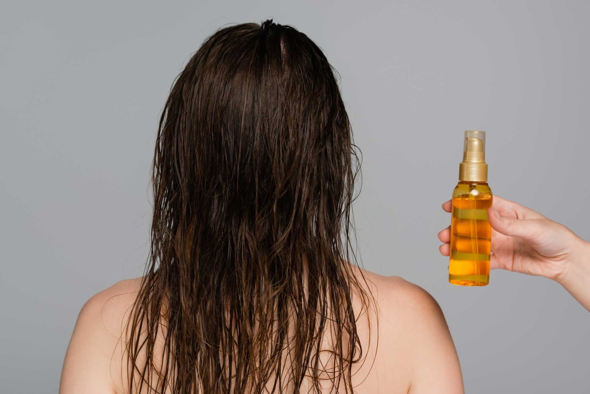 Person applying hair oil on wet hair