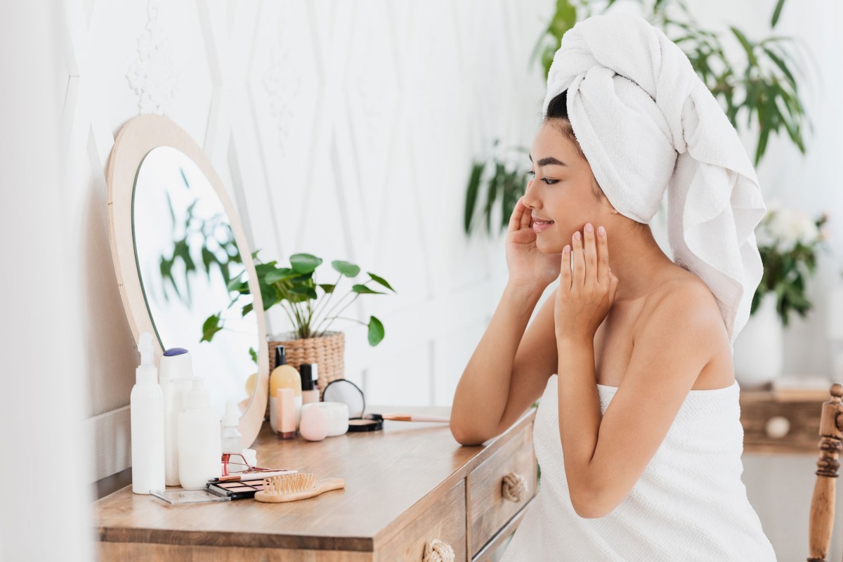 Woman applying skincare in a bright vanity room