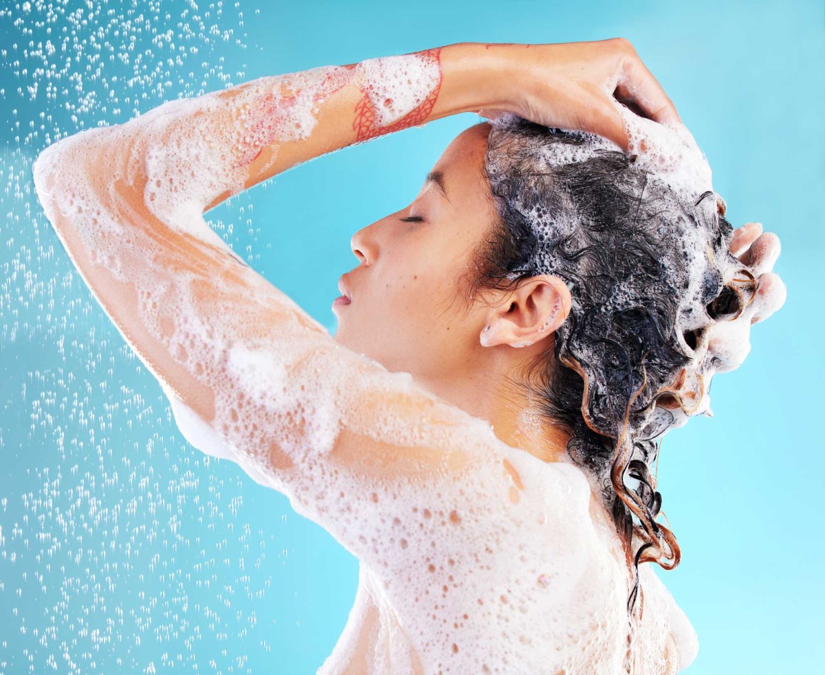 Woman washing hair with shampoo and foam