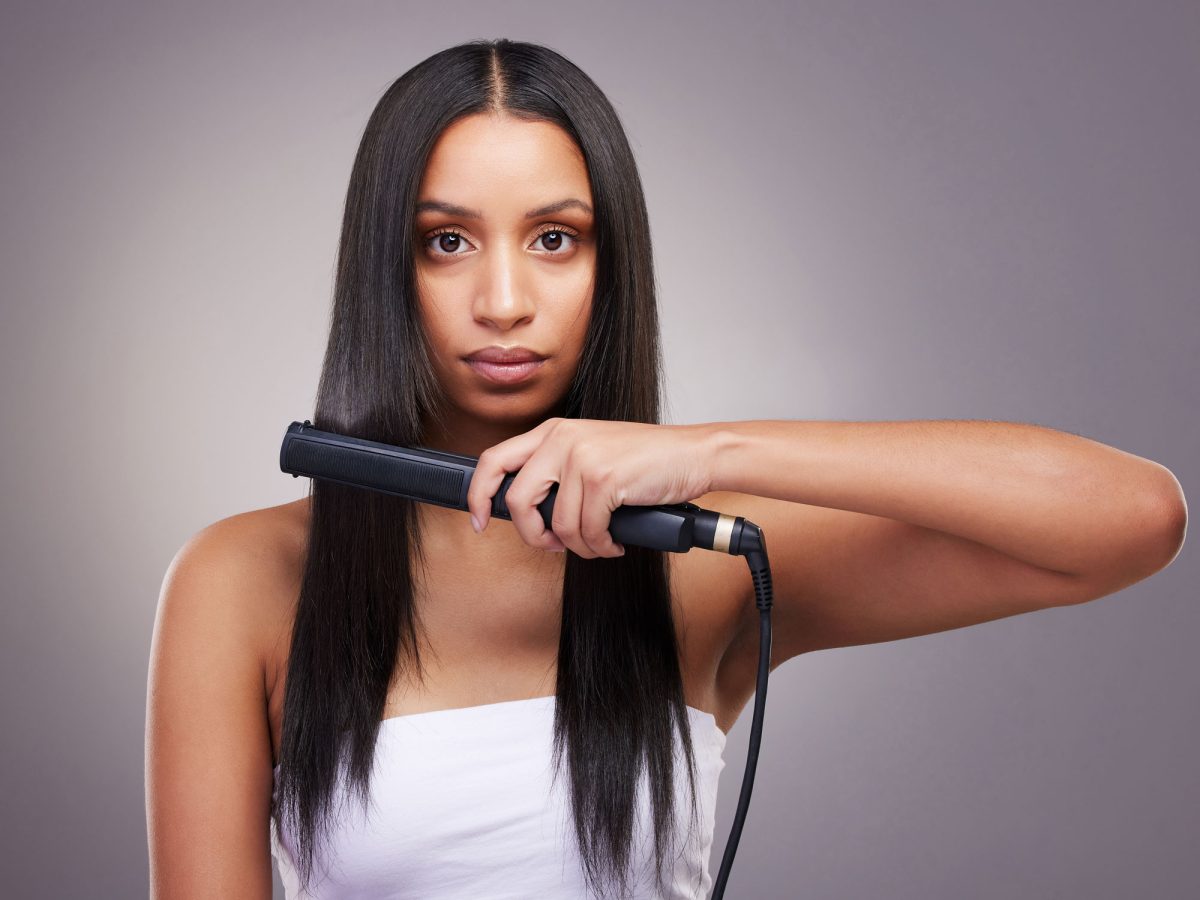 Woman using flat iron on her long straight hair