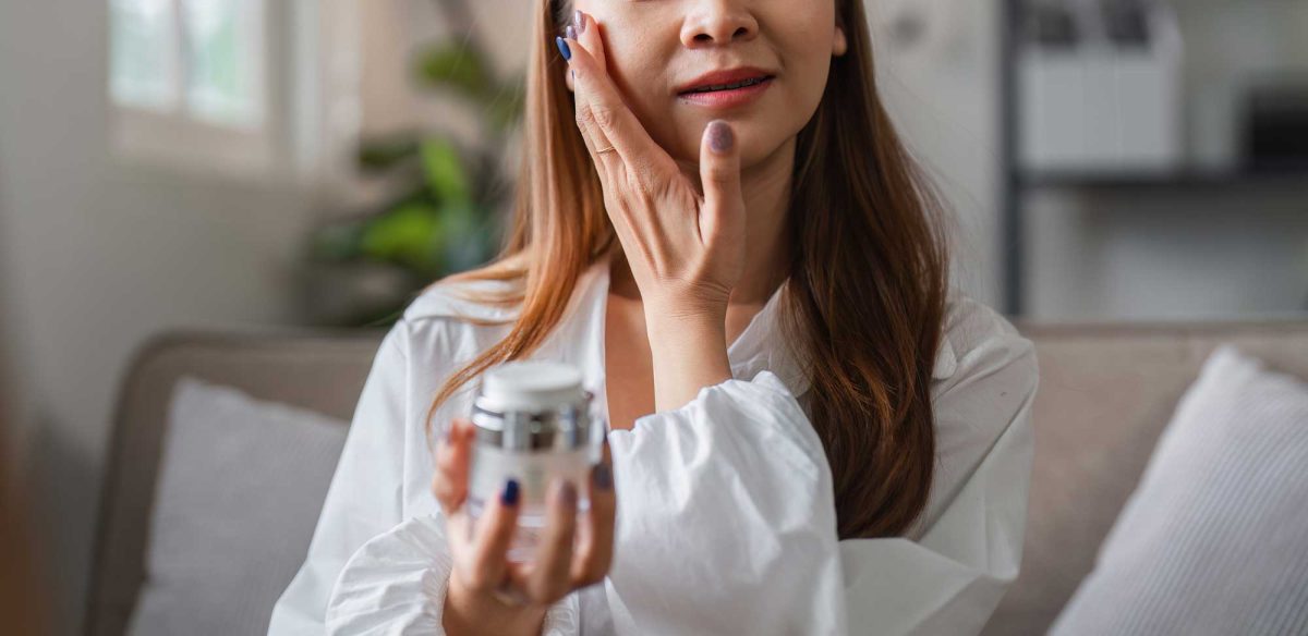 Woman applying facial cream at home