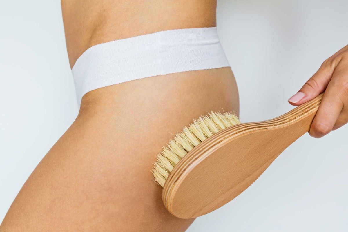 Person using dry brush on bare abdomen