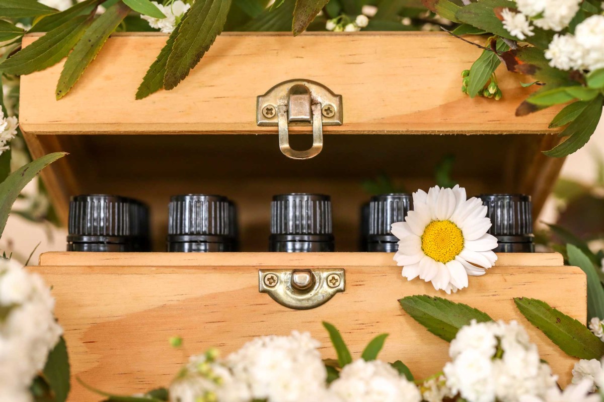 Essential oil bottles in wooden box with flowers