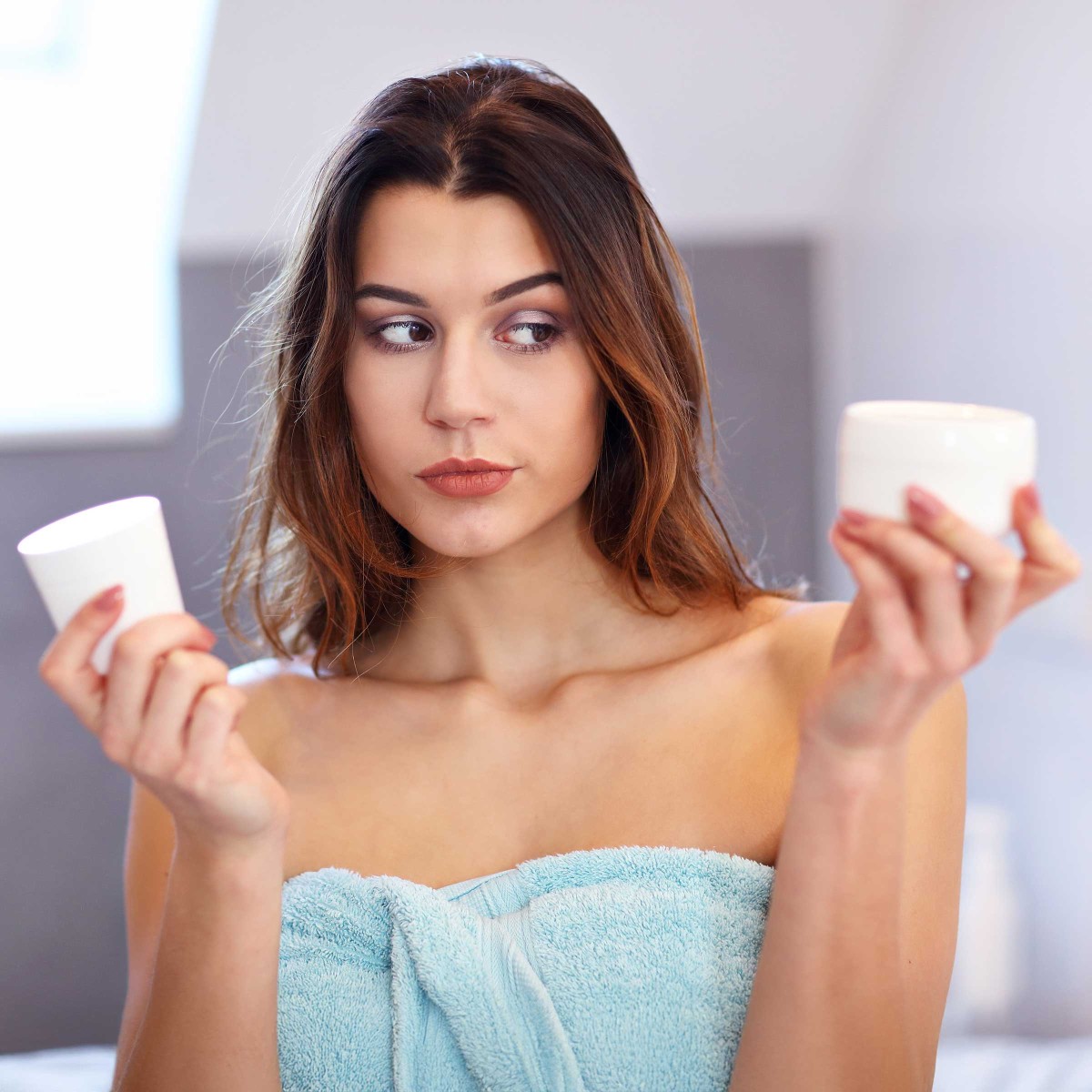 Woman comparing two skincare products in bathroom