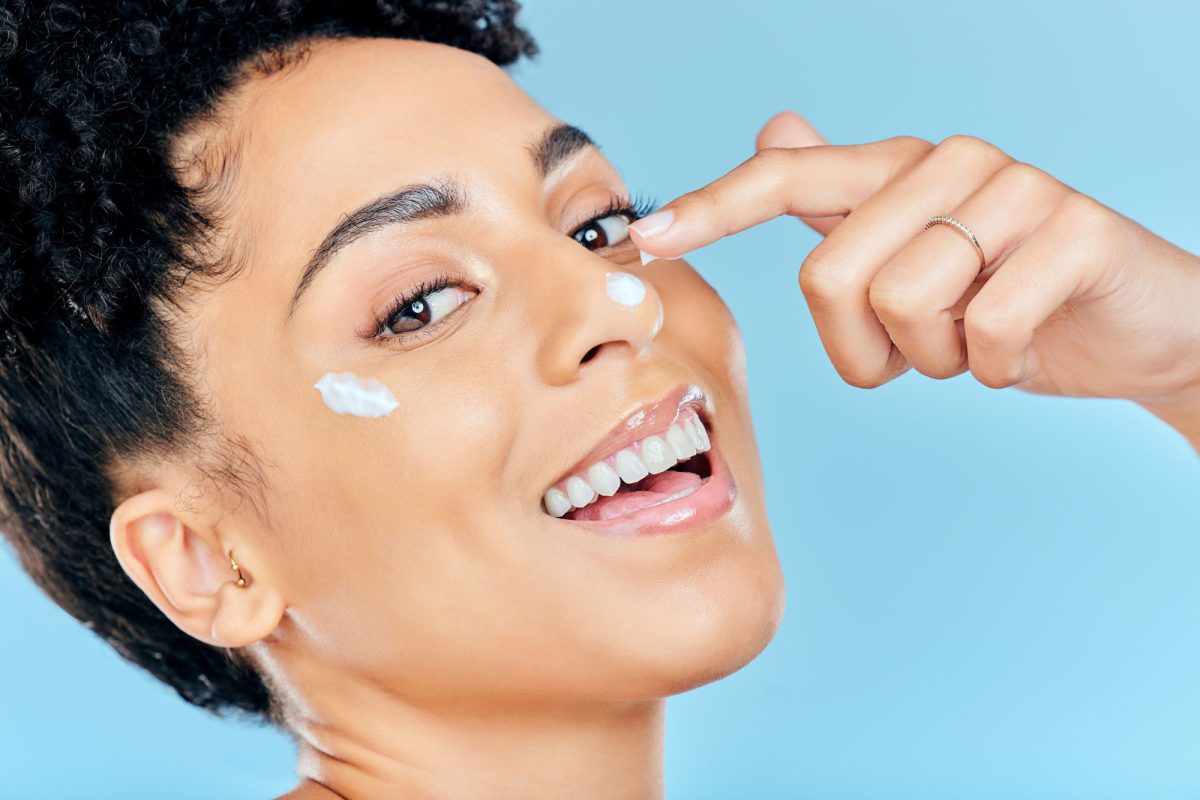 Woman applying facial cream, smiling joyfully