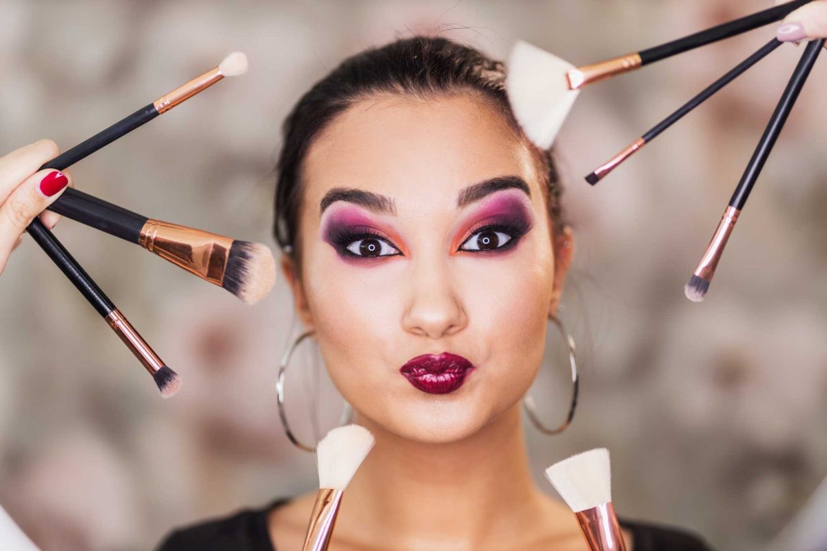 Woman with makeup surrounded by brushes