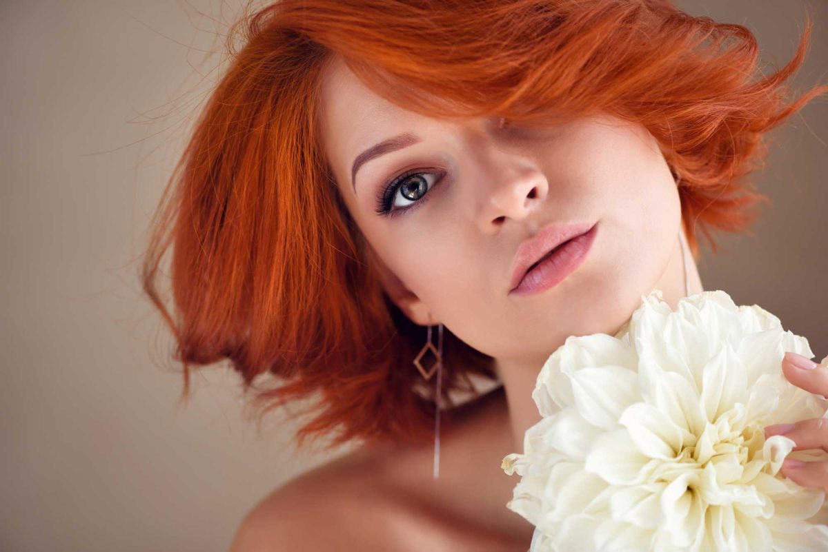 Red-haired woman holding white flower, close-up