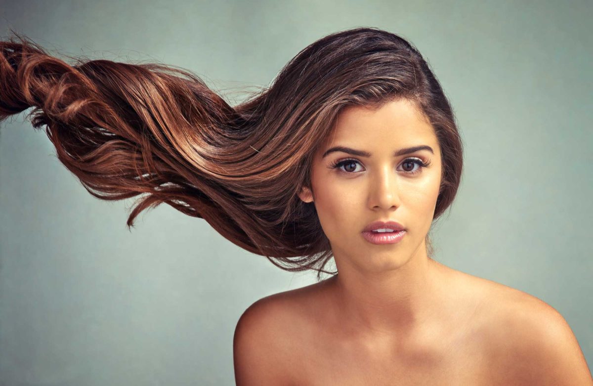 Woman with flowing long brown hair on teal background