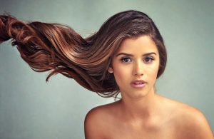 Woman with flowing long brown hair on teal background